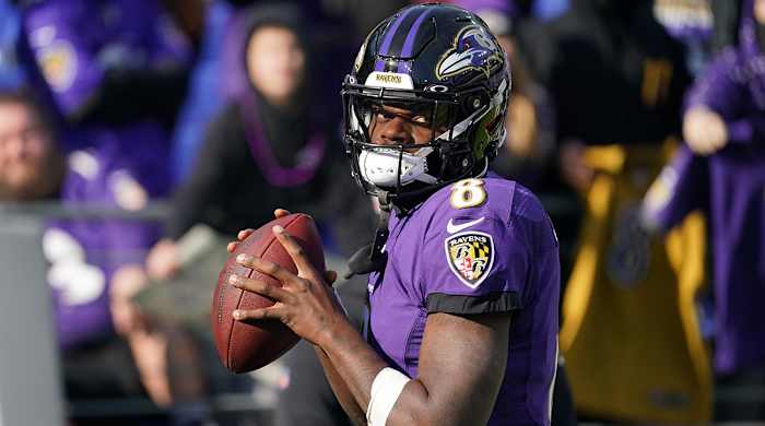 Lamar Jackson looks straight ahead while preparing to throw a football in warmups